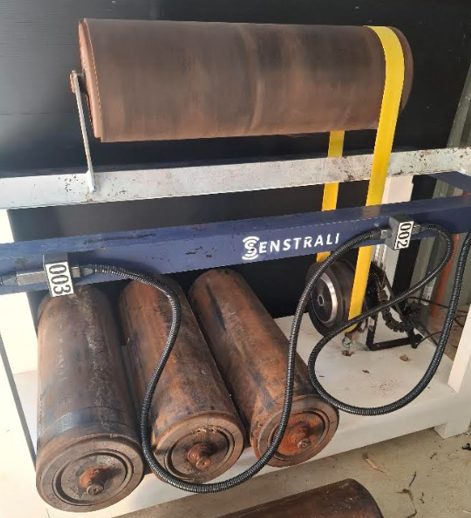 Multi-node cable on the bench rig, with used conveyor rollers below a Senstrali-branded frame